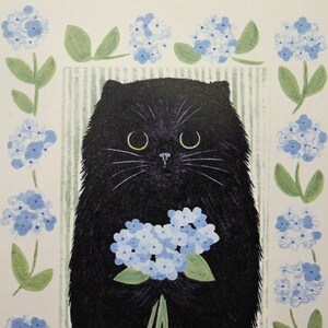 May include: A black cat with a bouquet of blue flowers. The cat is sitting in front of a white background with green leaves and blue flowers.