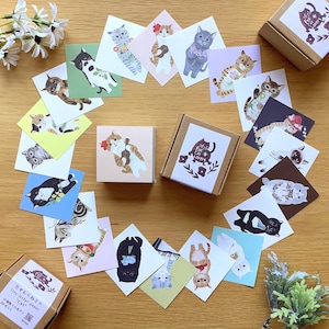 Puede incluir: Una colección de artículos de papelería con temática de gatos, que incluye pequeñas cajas cuadradas y tarjetas individuales. Las tarjetas presentan varias ilustraciones de gatos en diferentes poses y atuendos, dispuestas alrededor de las cajas. Las cajas tienen un logotipo con temática de gatos.