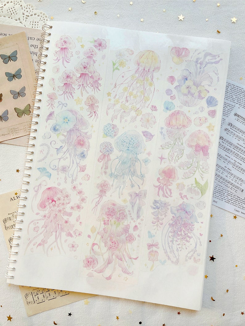 Puede incluir: Una hoja de papel de pegatina transparente con ilustraciones de acuarela coloridas de medusas y flores. Las medusas son transl&uacute;cidas y tienen tent&aacute;culos largos y flotantes. Las flores son en tonos de rosa, morado y azul.