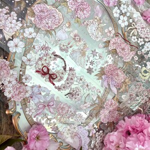 Puede incluir: Un espejo de estilo vintage adornado con un dise&ntilde;o floral. El espejo est&aacute; rodeado de flores rosas y una delicada puntilla blanca. El espejo refleja una variedad de patrones florales e im&aacute;genes de hadas.