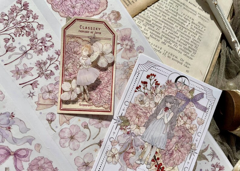 Puede incluir: Dos hojas de papel decorativo con un dise&ntilde;o floral. El papel presenta un delicado patr&oacute;n floral rosa y blanco con un efecto acuarela. El papel est&aacute; decorado con peque&ntilde;os detalles intrincados, incluyendo estrellas y lazos. El papel es perfecto para scrapbooking, la creaci&oacute;n de tarjetas y otros proyectos de manualidades.