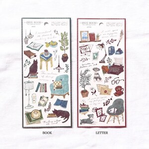 May include: Two sheets of stickers with illustrations of a cozy room with a cat, books, a chair, a lamp, and a plant on one sheet and a dog, a typewriter, a letter, and a plant on the other sheet. The text "Snug Room" is at the top of each sheet. The words "Book" and "Letter" are printed below each sheet.