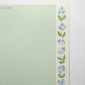 May include: A light green postcard with the word "POSTCARD" printed in the top left corner. The right edge of the postcard has a white border with a repeating pattern of blue flowers and green stems.