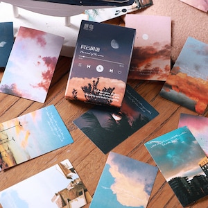 May include: A set of decorative cards featuring various images of clouds, sky, and cityscapes. The cards have a vintage aesthetic and include text in Chinese and English. The text on the cards reads "The wind of the moon" and "Where your presence be it what it was the sky and what is within".