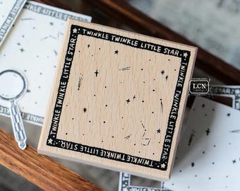 May include: A wooden stamp with the text "TWINKLE TWINKLE LITTLE STAR" around the border. The stamp features a constellation design with stars and lines. Other star-themed stationery items are in the background.