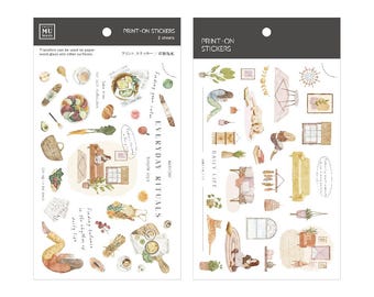 May include: Two sheets of print-on stickers featuring watercolor illustrations of everyday objects and scenes. One sheet is titled "Everyday Rituals" and the other "Daily Life". The stickers include food, furniture, and figures.