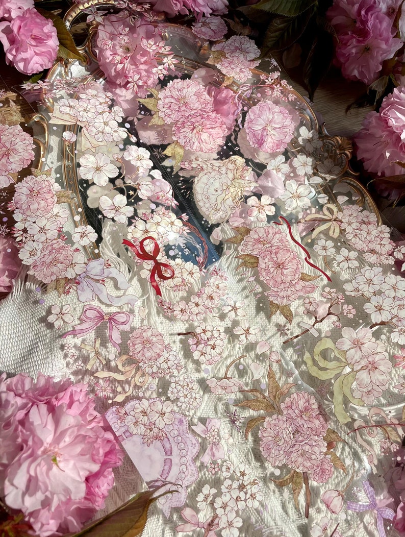 Puede incluir: Una bandeja decorativa con un dise&ntilde;o floral que presenta flores de cerezo rosas y detalles dorados. La bandeja est&aacute; hecha de vidrio transparente y tiene una est&eacute;tica delicada y femenina.
