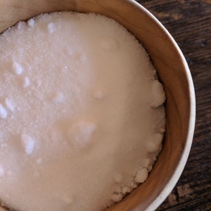 May include: A wooden bowl filled with white salt crystals.