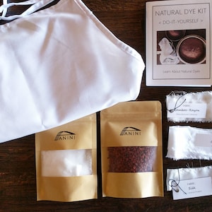 May include: Natural dye kit with instructions, two brown paper bags with white powder and red dye, and four white fabric swatches labeled "Bamboo-Rayon", "Cotton", "Silk", and "Cotton".