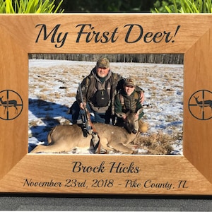 May include: A wooden photo frame with a personalized inscription that reads "My First Deer!"  The frame features a photo of two people posing with a deer. The inscription also includes the name "Brock Hicks", the date "November 23rd, 2018", and the location "Pike County, IL".