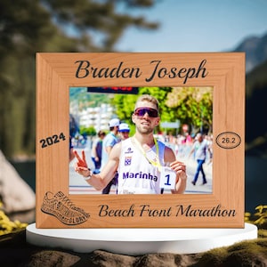 May include: A wooden photo frame with a runner in the photo. The frame is engraved with the text "Braden Joseph", "2024", "Beach Front Marathon", and "26.2".