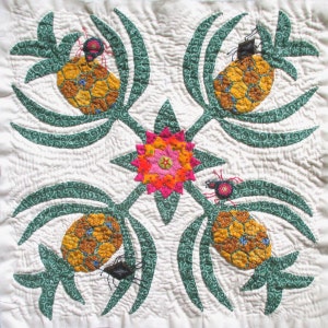 May include: A square quilt with a repeating pattern of stylized pineapples, green leaves, and insects. The pineapples are yellow and brown, the leaves are green, and the insects are black and red. A central flower is pink, orange, and yellow.