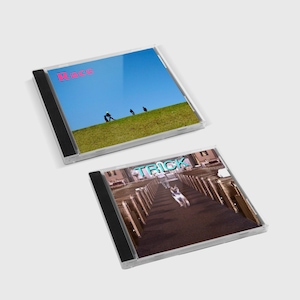 Può includere: Due custodie per CD. La custodia superiore ha uno sfondo di cielo blu con la parola "Race" in rosa. La custodia inferiore ha una foto di un cane che corre in un corridoio con la parola "Trick" in turchese.