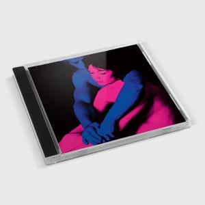 Può includere: Una custodia per CD con sfondo nero e una coppia che si abbraccia. La donna indossa una camicia rosa e l'uomo una camicia blu. L'immagine è in uno stile ad alto contrasto.