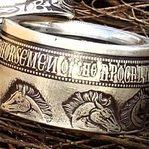 a close up of a silver ring with horses on it