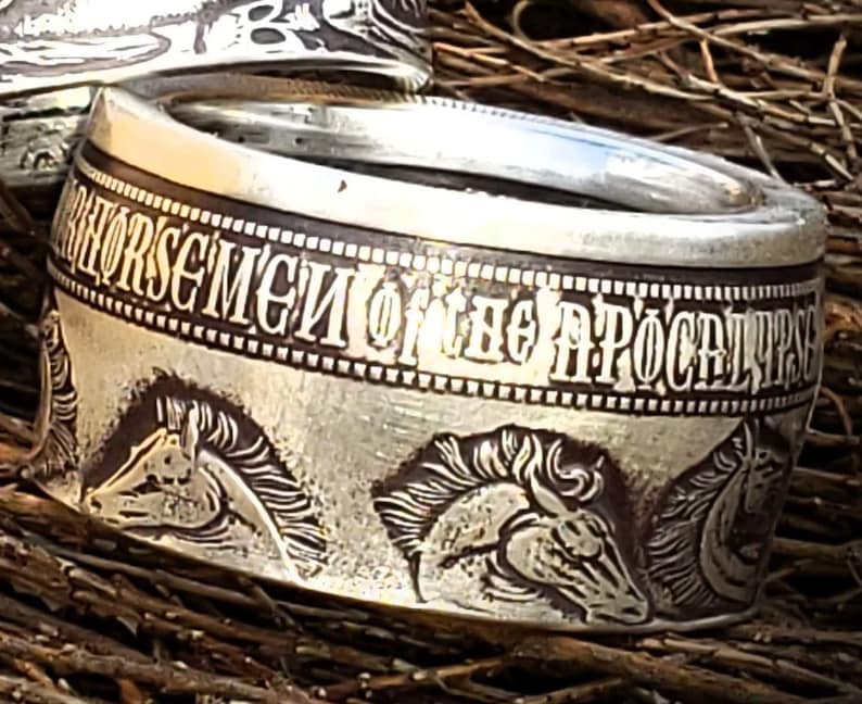 a close up of a silver ring with horses on it
