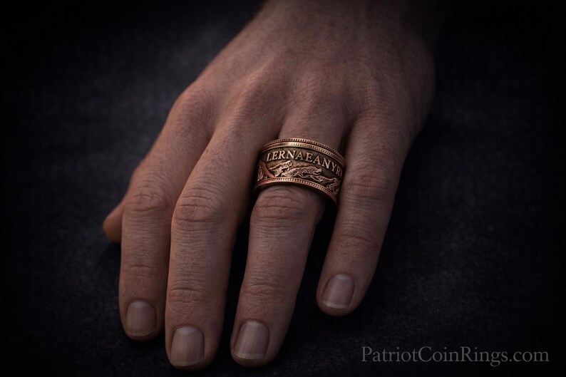 A close-up of a person's hand wearing a ring with the word "LERNA" engraved on it.