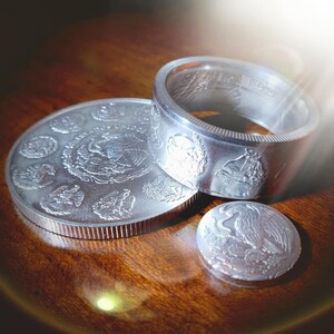 two silver coins sitting on top of a wooden table