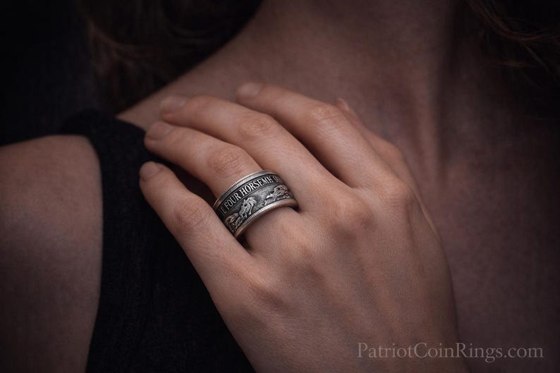 A close-up of a person's hand wearing a silver ring with a decorative design.