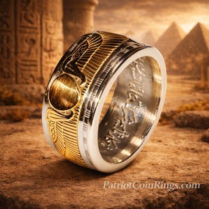 A gold and silver ring with intricate designs, placed on a rock against a backdrop of ancient Egyptian ruins and pyramids.
