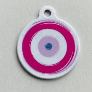 May include: A white circular charm with a pink and white evil eye design. The eye is surrounded by a thick pink ring.