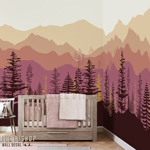 May include: A nursery wall decal featuring a silhouette of a mountain range with a forest in the foreground. The mountains are in shades of pink, orange, and yellow, while the trees are dark brown and yellow. The decal is perfect for adding a touch of nature to a child's room.