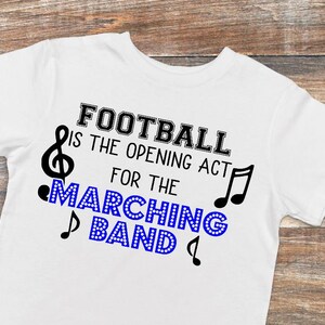 May include: White t-shirt with black text that reads "Football is the opening act for the marching band". The text is surrounded by musical notes.