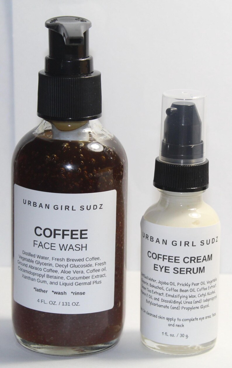 May include: Two glass bottles of coffee-based skincare products. The larger bottle is a brown liquid face wash labeled "URBAN GIRL SUDZ COFFEE FACE WASH" with instructions to "lather, wash, rinse". The smaller bottle is a white cream eye serum labeled "URBAN GIRL SUDZ COFFEE CREAM EYE SERUM".