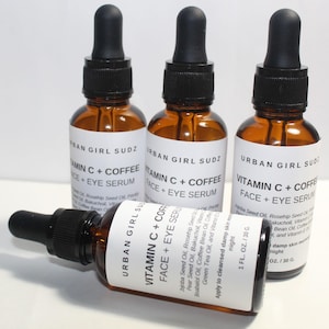 Op de afbeelding: Drie bruine glazen flessen met zwarte druppelaars en witte etiketten. De etiketten lezen "Urban Girl Sudz Vitamin C + Coffee Face + Eye Serum". De flessen bevatten 30 ml serum.