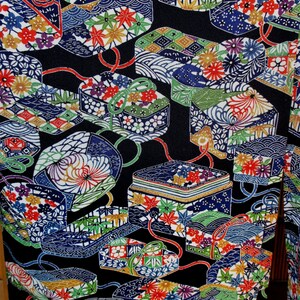 May include: A black fabric with a repeating pattern of colourful boxes and flowers. The boxes are decorated with gold and white designs. The flowers are in shades of pink, red, yellow, and blue.