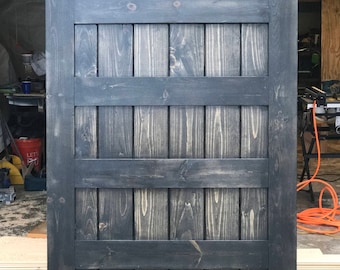 May include: A dark gray wooden sliding barn door with a horizontal plank design. The door is made of vertical wood planks with a dark stain finish.