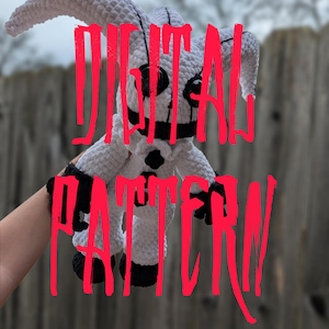 May include: A white and black crocheted doll with large black eyes and a stitched mouth. The doll has long, floppy ears and black accents on the hands and feet. The words "DIGITAL PATTERN" are written across the image in red.