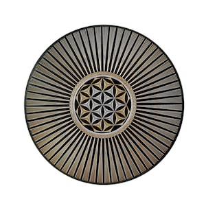 Könnte beinhalten: Ein schwarzer und goldener runder Wandbehang mit einem geometrischen Design in der Mitte. Das Design ist ein Lebensblume-Muster mit silbernem Umriss.