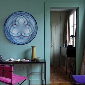 May include: A teal room with a black desk and a pink chair. A large blue and white geometric wall hanging is on the wall above the desk. A yellow lamp is on the left side of the desk and a vase with a brown bowl is on the right side of the desk.