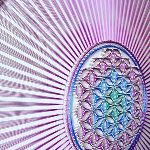 May include: A purple, blue, and green string art wall hanging featuring a flower of life design.