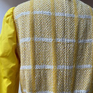 May include: Yellow and white checkered jacket with a yellow collar and a yellow tag on the back.