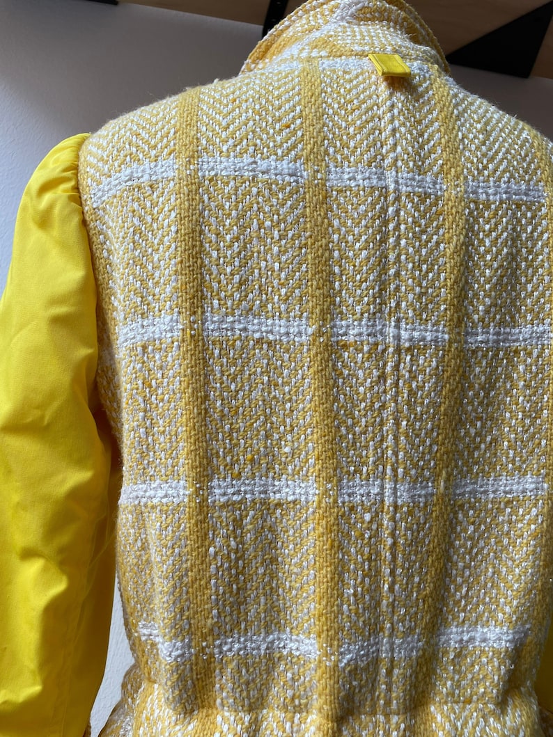 May include: Yellow and white checkered jacket with a yellow collar and a yellow tag on the back.