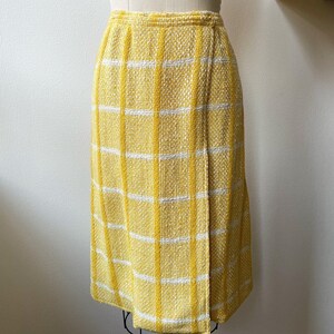 May include: A yellow and white plaid skirt with a wrap style design. The skirt is knee-length and has a straight silhouette.