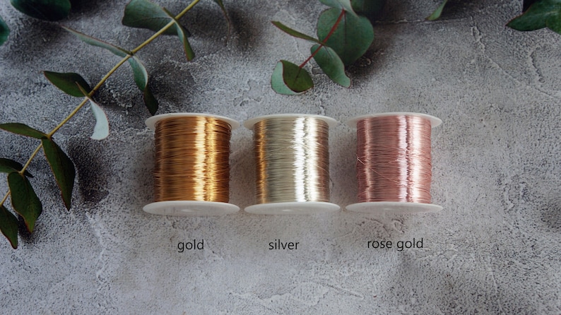 Puede incluir: Tres carretes de alambre, uno dorado, uno plateado y uno de oro rosa. Los carretes est&aacute;n etiquetados como "gold", "silver" y "rose gold".
