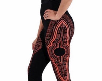 May include: Black leggings with a vibrant orange tribal pattern. The leggings feature a high waist and a detailed design that runs down the sides and legs. A black tank top completes the outfit.