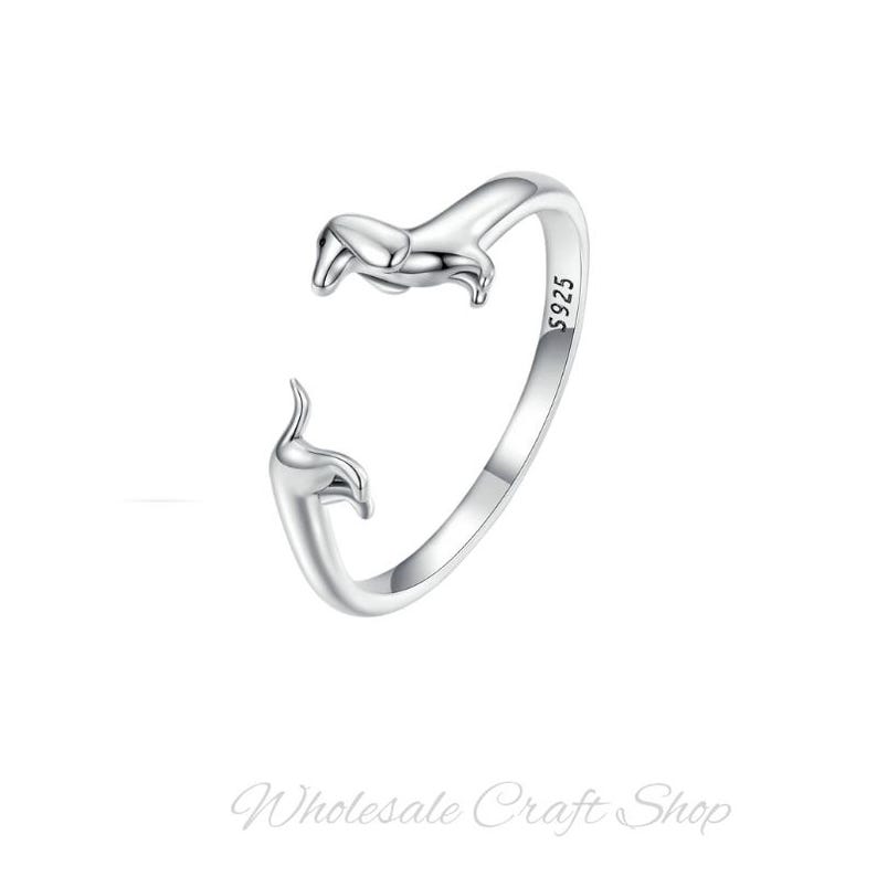 Peut inclure: Une bague en argent avec un motif de teckel. La bague est ouverte et le teckel fait face au porteur. La bague est marqu&eacute;e "S925" sur le c&ocirc;t&eacute;.