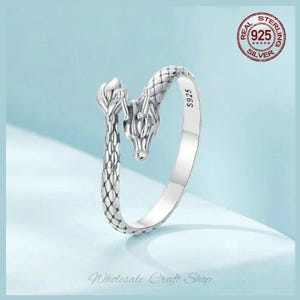 May include: Silver ring featuring a detailed dragon design. The ring is adjustable and has the inscription "S925" on the band.