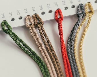 May include: A close-up of a color chart with different shades of green, beige, brown, red, gray, and yellow cord. The cords are arranged in a row, with the green cord at the top and the yellow cord at the bottom.