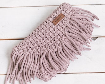 May include: A light pink crocheted scarf with long fringe and a brown leather tag that says "MONOMEY".