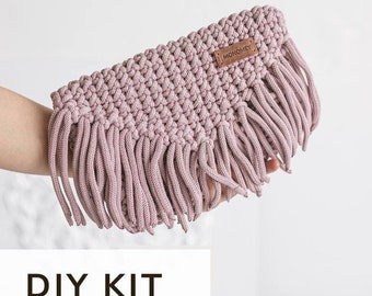 May include: DIY kit for a pink crocheted clutch with a leather tag that says "Monomey". The clutch has a fringe detail.