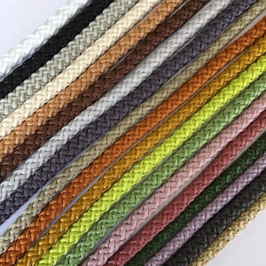May include: A collection of 20 different coloured braided cords. The cords are arranged in a diagonal pattern, with the lightest colours at the top and the darkest colours at the bottom.