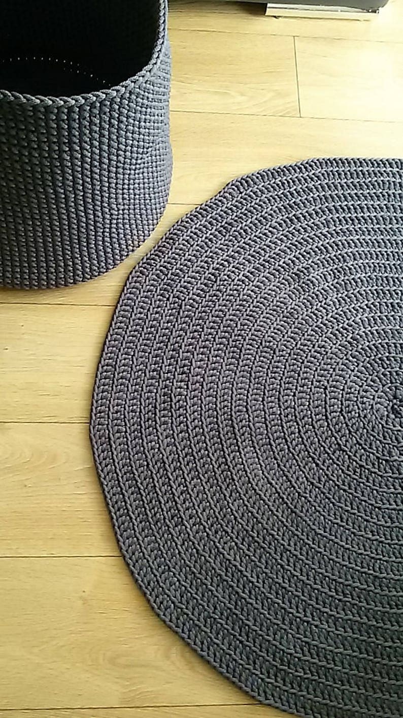 May include: A gray round crocheted rug with a circular pattern. The rug is made of thick yarn and has a textured surface.