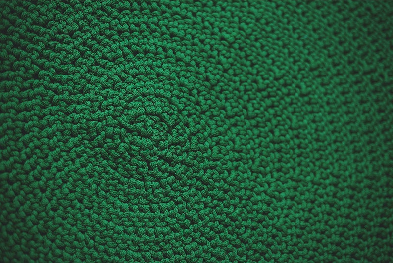 May include: Close-up of a green textured fabric with a repeating pattern of small loops.