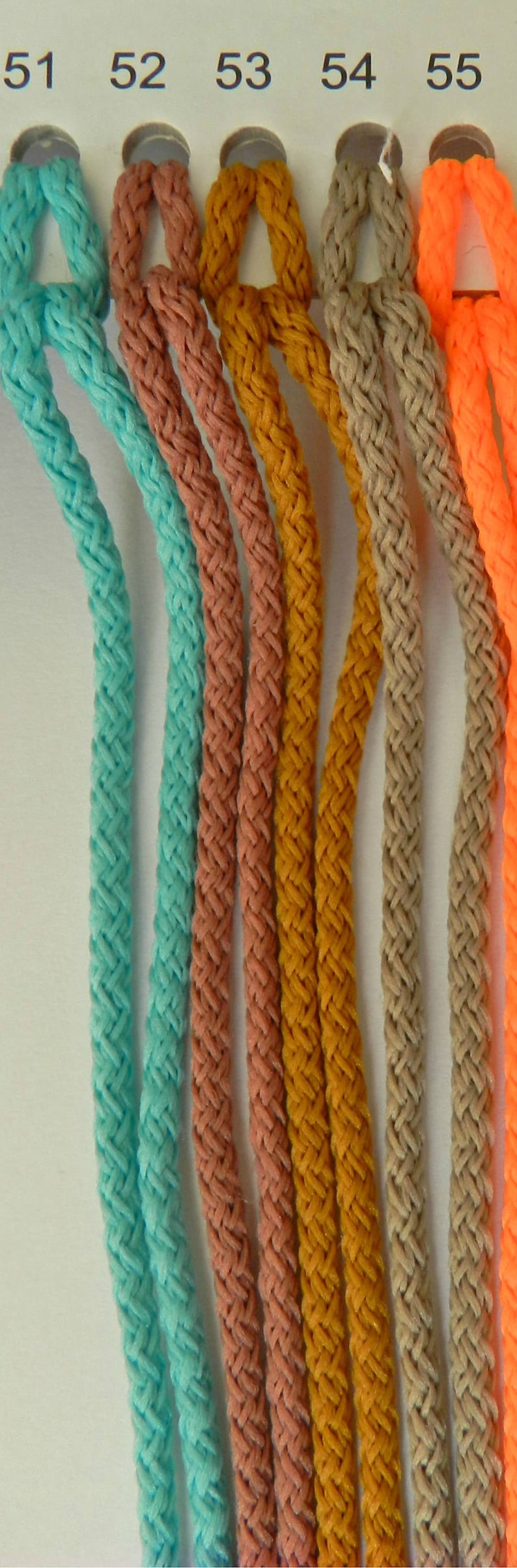 May include: A close-up of six braided cords in various colors: turquoise, coral, mustard yellow, tan, and bright orange. The cords are looped at the top and numbered 51 through 55. The cords are made of a soft, flexible material.