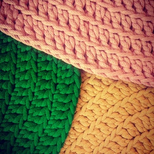 May include: Three sections of knitted fabric in different colors: pink, green, and yellow. The fabric is woven in a simple, repeating pattern.